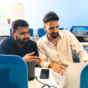 Team members collaborating at Ethersoftex IT Solutions office with laptops, indoor plants, and a modern workspace.